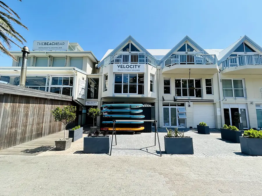 The Velocity Gym building: white clapboard gables with the VELOCITY sign over the entrance, under a blue sky