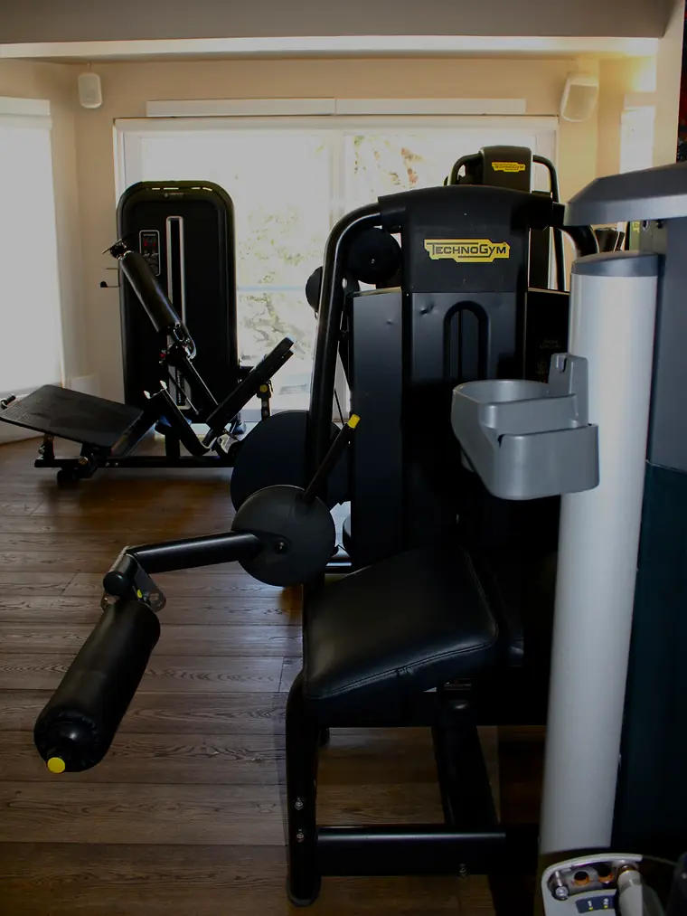 A Technogym leg extension on the timber floor by the windows