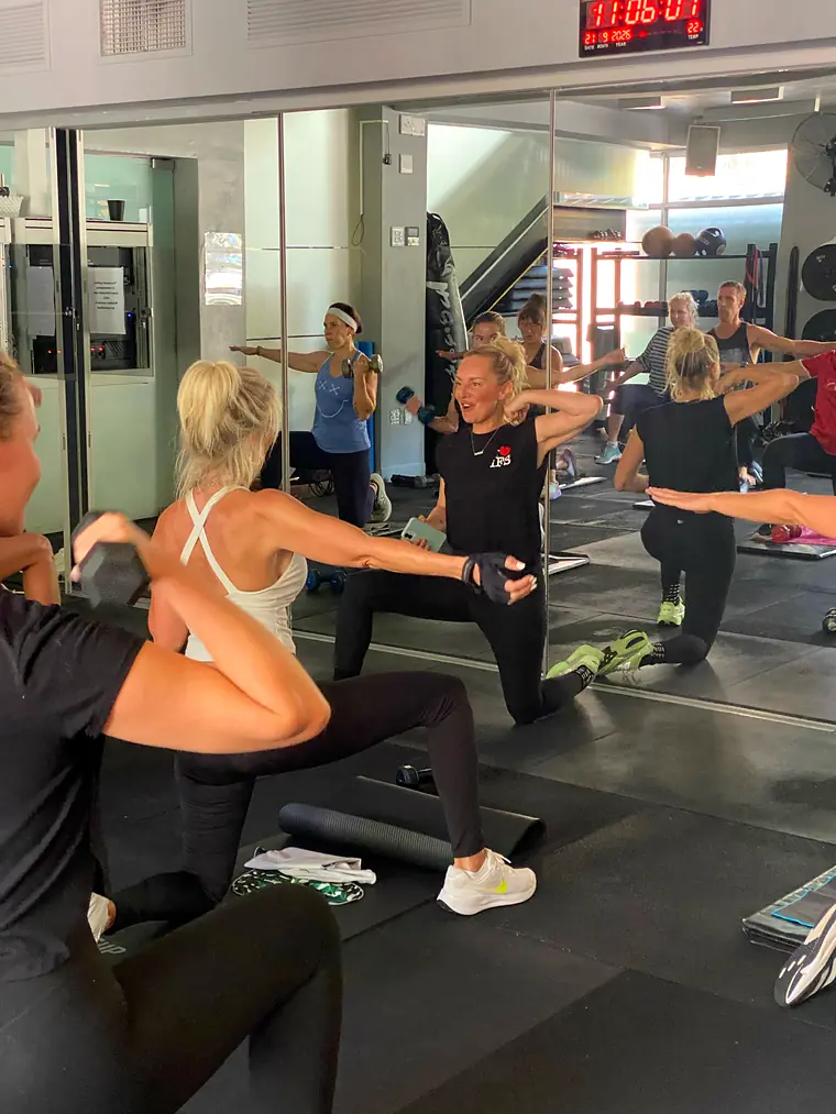 A SWEAT class training in front of the mirrors, the red interval timer on the wall
