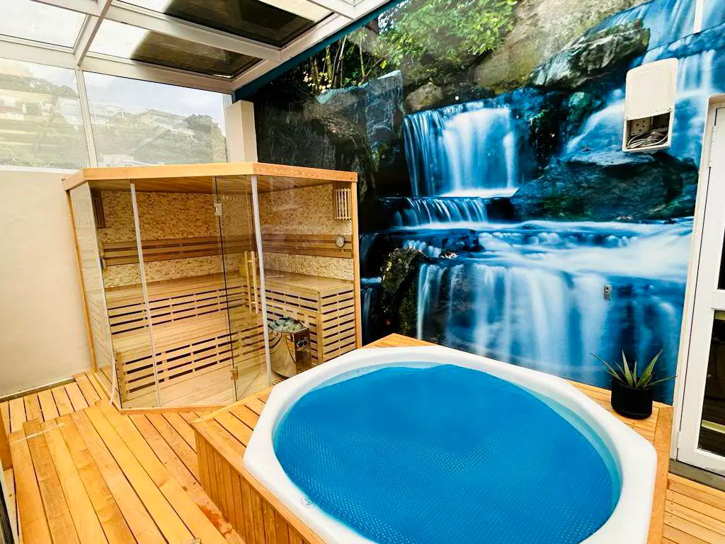 The wellness area: a timber sauna cabin beside a round plunge pool